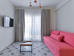 a living room with a pink couch and a table at KaSta Family Apartments in Nikiti
