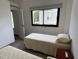 Un dormitorio pequeño con dos camas y una ventana. en La Escondida Salta 1, en Salta