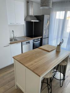 a kitchen with white cabinets and a wooden counter top at Superbe appartement au calme avec vue sur le Lac. in Évian-les-Bains