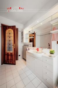 a white bathroom with a sink and a door at B&B Santa Libera in Monastero Bormida