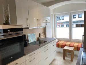 een keuken met witte kasten, een wastafel en een raam bij Ferienwohnung Roth, Unlingen in Unlingen