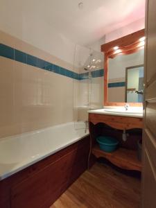 La salle de bains est pourvue d'une baignoire, d'un lavabo et d'un miroir. dans l'établissement Appartement Le Sorbier à Chamrousse 3 pièces 6 personnes aux pieds des pistes, à Chamrousse