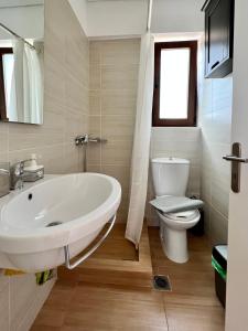 La salle de bains est pourvue d'un lavabo blanc et de toilettes. dans l'établissement Sunrise Studio with unhindered view to the sea., à Nea Makri