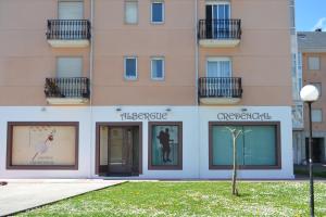 un edificio con dos ventanas y un árbol delante de él en Albergue Credencial, en Sarria