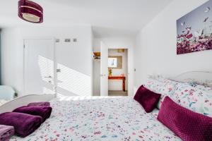 Dormitorio blanco con cama con almohadas moradas en Spire View - New Forest Holiday Home, en Lyndhurst