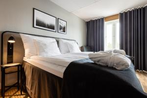 ein Schlafzimmer mit einem großen Bett mit weißer Bettwäsche und Kissen in der Unterkunft Clarion Collection Hotel Etage in Västerås