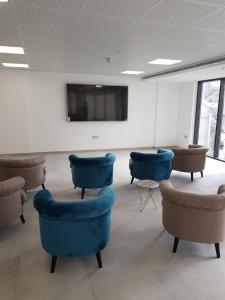 um quarto com cadeiras azuis e uma televisão de ecrã plano em The Hub Gibraltar Sacha studio em Gibraltar