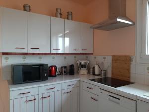 a kitchen with white cabinets and a microwave at Villa des petites Chaumes in Avallon +6 photos