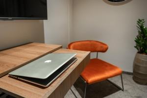 an apple laptop on a wooden table with a chair at DeGrassi Boutique Garni Hotel Izola in Izola