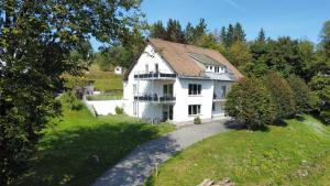 una gran casa blanca en una colina con árboles en Smart Resorts Haus Opal Ferienwohnung 404, en Winterberg