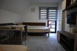 a bedroom with a bed and a table and a television at Apartman Vukašin in Kopaonik