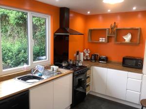 a kitchen with orange walls and a stove and a sink at Harbour View in Wick