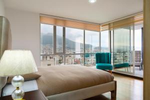 sypialnia z łóżkiem i dużym oknem w obiekcie Olympus Apartments w mieście Quito