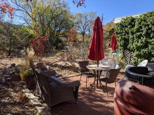 een patio met een tafel en stoelen en een rode parasol bij Studio apartment 15 minute walk to plaza in Santa Fe