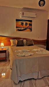 sypialnia z dużym łóżkiem z obrazem na ścianie w obiekcie Japaratinga Suites w mieście Japaratinga