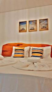 a bedroom with a large bed with three paintings on the wall at Japaratinga Suites in Japaratinga