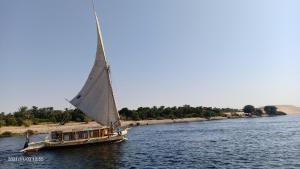 een boot met een groot zeil op een rivier bij JJ Jamaica Felucca in Aswan