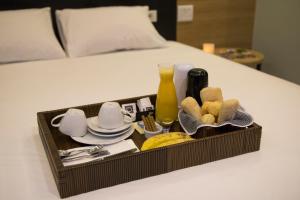 uma bandeja com comida e utensílios numa cama em Drops Express Motel em Barretos