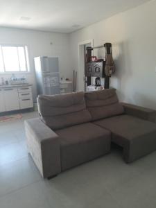 a brown couch in a living room with a kitchen at Apartamento FLAT no centro - Passo de Torres SC in Pirataba