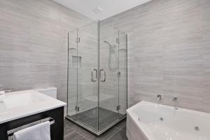 a bathroom with a shower and a tub and a sink at Grand Suites Murchison in Murchison