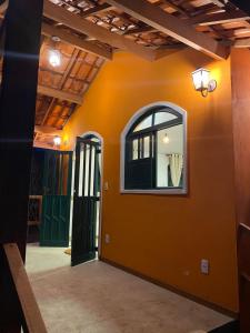 ヴァレ・ド・カパオンにあるManacá Chalés do Valeのオレンジ色の壁と窓が特徴の客室です。