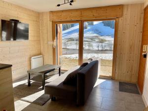 ein Wohnzimmer mit einem Sofa und einem großen Fenster in der Unterkunft Gîte avec terrasse et belle vue - ChaletNelda com in Lamoura