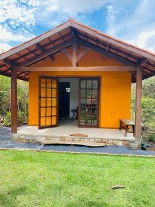een klein geel huis met een bankje ervoor bij Manacá Chalés do Vale in Vale do Capao