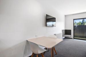 a white dining room with a white table and chairs at Grand Suites Murchison in Murchison