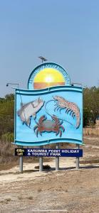 a sign on the side of a beach with a fish at Karumba Point Holiday & Tourist Park in Karumba