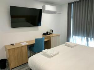 um quarto de hotel com uma cama, uma secretária e uma televisão em The Osmond Motel & Apartments em Adelaide