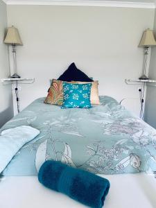 a blue blanket laying on a bed with two lamps at Churchill's B&B twin spa getaway Studio in Swansea