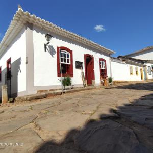 un edificio bianco con finestre rosse e una porta rossa di Pousada Casa Direita a Tiradentes