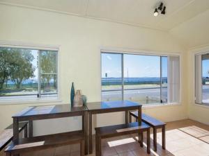 a room with a table and two benches and windows at Stillwater large cottage across from the water sleeping 13 in Nelson Bay