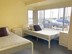 a bedroom with two beds and a window with a car outside at Stillwater large cottage across from the water sleeping 13 in Nelson Bay