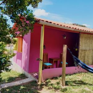 a pink house with a hammock in front of it at Chalés Encantos de Cunha Rosa in Cunha