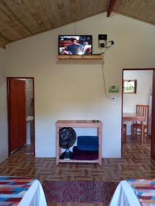 a room with a tv on the wall and a fan at Chalés Encantos de Cunha Rosa in Cunha