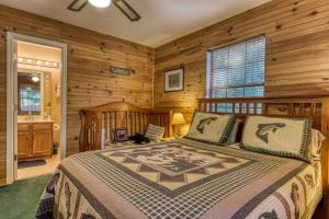 a bedroom with a bed in a room with wooden walls at Sunset Ridge Cabin - A Romantic Smoky Mountain Escape or Family Getaway - behind Dollywood, large game room, jacuzzi tub, fire pit, large wrap-around deck, and more in Pigeon Forge