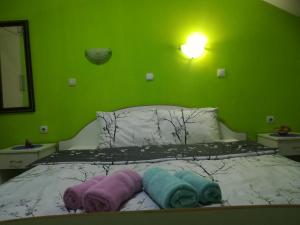 Karoski Apartments & Suites في أوخريد: غرفة نوم خضراء عليها سرير وفوط