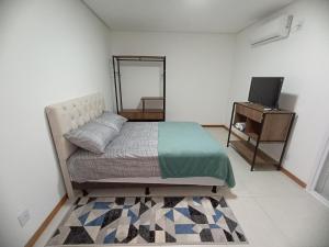 ein Schlafzimmer mit einem Bett, einer Kommode und einem TV in der Unterkunft Flat Santa Cruz II in Santa Cruz do Sul