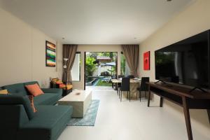 uma sala de estar com um sofá, uma televisão e uma mesa em Tea Tree Boutique Resort em Praia de Rawai
