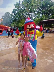 una niña pequeña y una niña parada junto a una mascota en Paragon Water Themepark Suites by GGM en Melaka