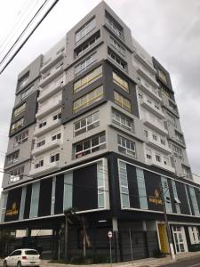 um edifício cinza alto com um carro estacionado em frente dele em RESIDENCIAL Montevideo em Osório