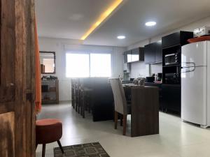 a kitchen with a white refrigerator and a table with chairs at RESIDENCIAL Montevideo in Osório