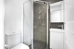 Coogee Studio Apartments في سيدني: حمام مع دش مع مرحاض ومغسلة