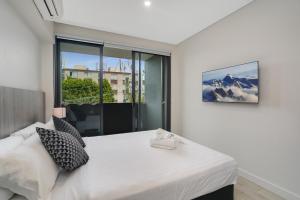 a bedroom with a white bed and a large window at Coogee Studio Apartments in Sydney
