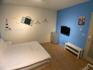 1 dormitorio con 1 cama blanca y TV en Lazy bone, en Hsinchu City