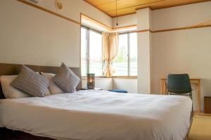 a bedroom with a large white bed with a window at T Square Hakuba in Otari