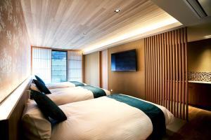a hotel room with three beds and a television at Kikokutei Bekkan in Kyoto