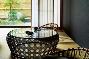 a glass table with two chairs and a window at Kikokutei Bekkan in Kyoto