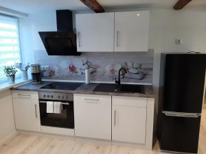 a kitchen with white cabinets and a black refrigerator at Ferienwohnung Alte Glaserei in Ilsenburg